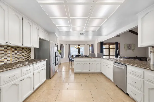 a large white kitchen with granite countertop lots of white stainless steel appliances