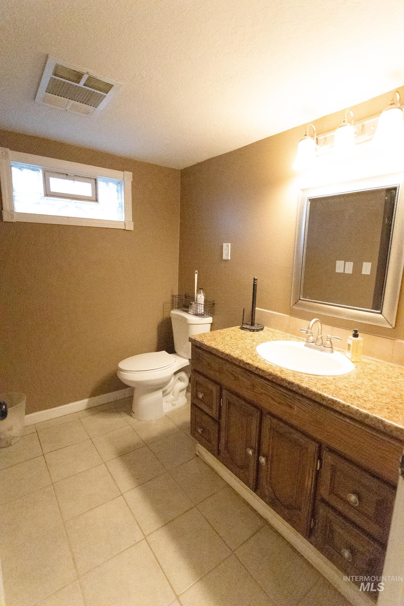 1400 Anderson Corner Road Parma, ID 83660 - Photo 13 of 31 Half bathroom featuring vanity, light tile patterned floors, and a textured ceiling