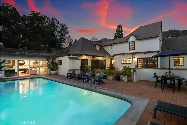 a view of a swimming pool with lawn chairs under an umbrella