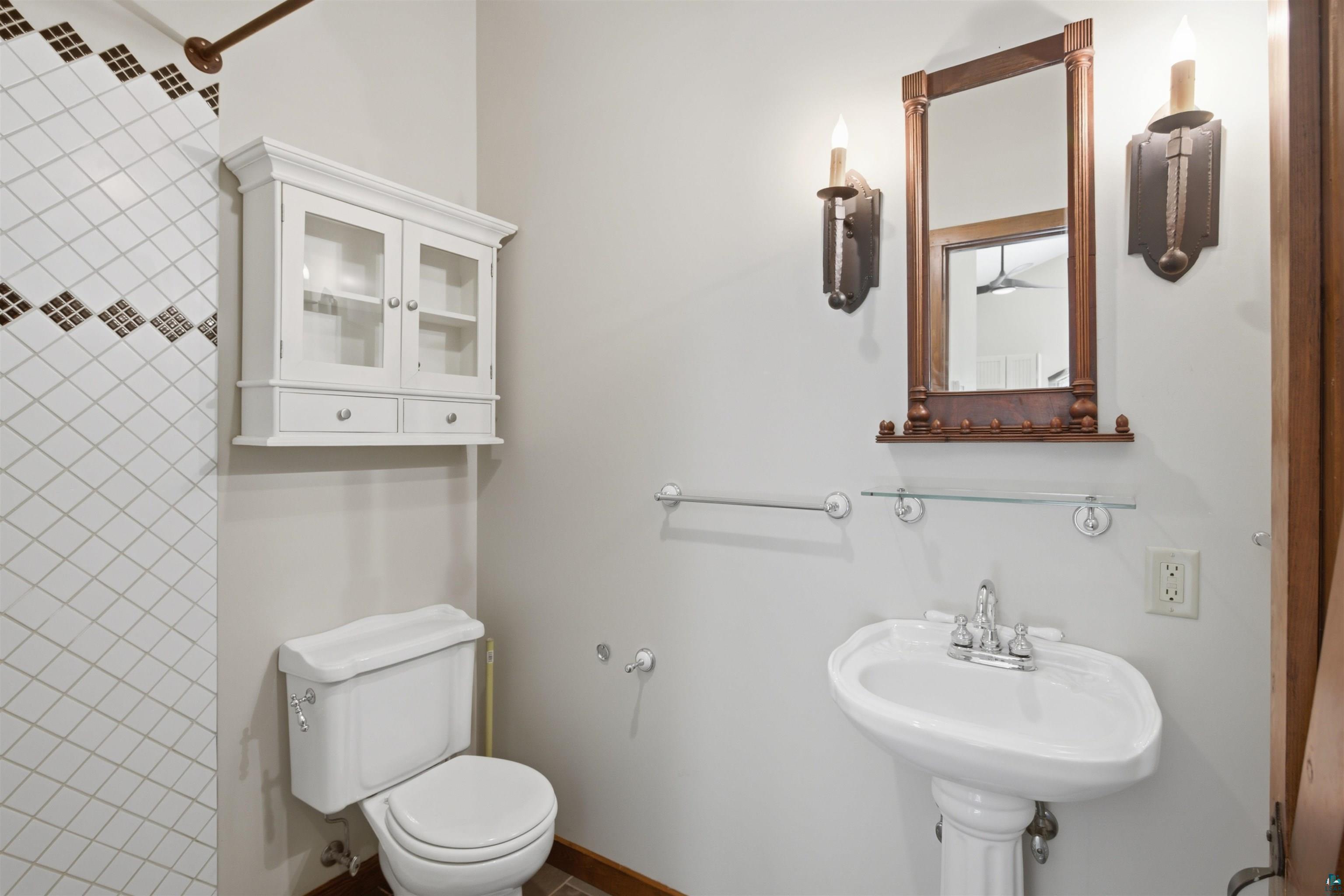 86270 Meyers-Olson Road Bayfield, WI 54814 - Photo 18 of 33 White pedestal sink with chrome faucet, complemented by a decorative wood-framed mirror