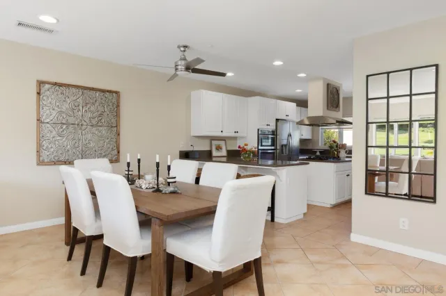 a dining room with stainless steel appliances kitchen island granite countertop a dining table chairs and view living room