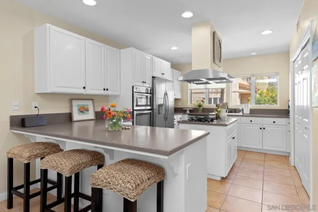 a kitchen with stainless steel appliances granite countertop a table chairs sink and cabinets