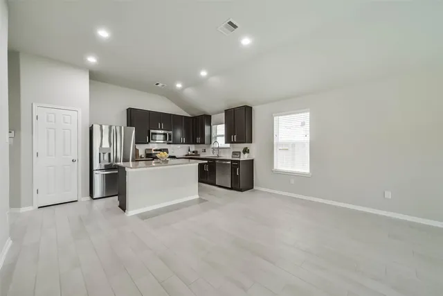 a large kitchen with a large counter top stainless steel appliances and cabinets