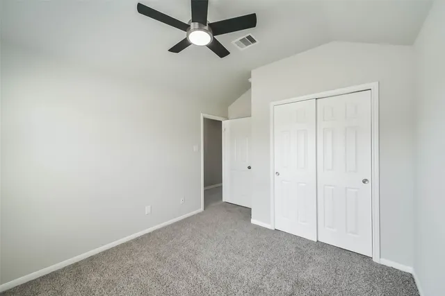 an empty room with a ceiling fan and closet