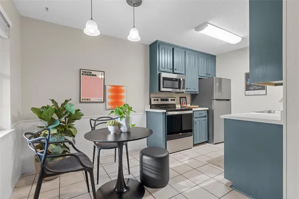 a kitchen with stainless steel appliances a dining table chairs stove refrigerator and microwave