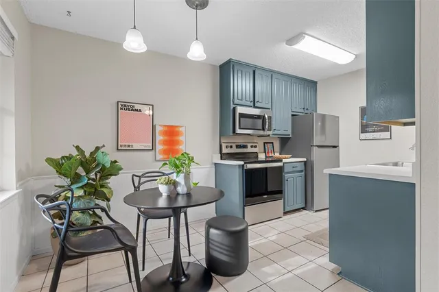 a kitchen with stainless steel appliances a dining table chairs stove refrigerator and microwave