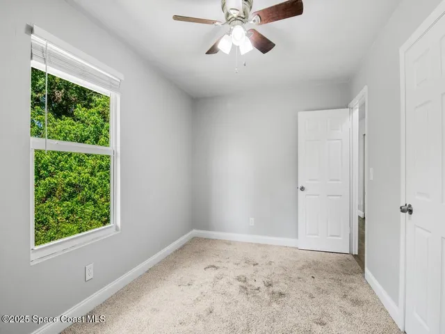 a view of empty room with a window and a ceiling fan