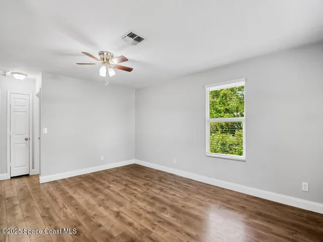 an empty room with a window and a ceiling fan