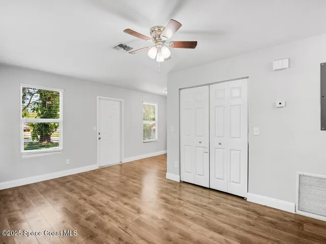 a view of an empty room with wooden floor and a window