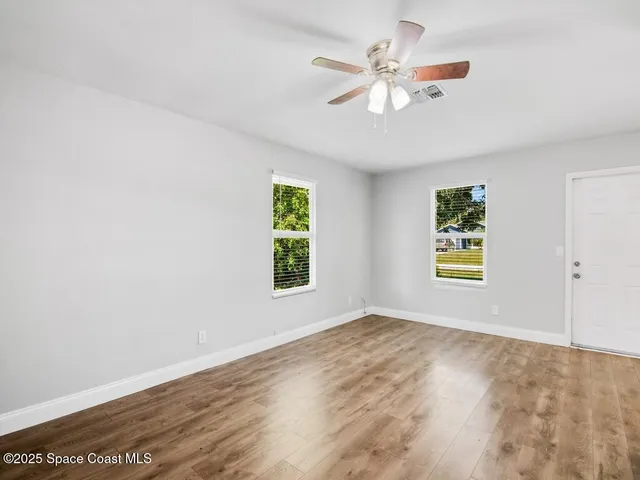 an empty room with windows and fan