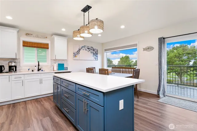 a kitchen with a stove a sink a large window with wooden floor