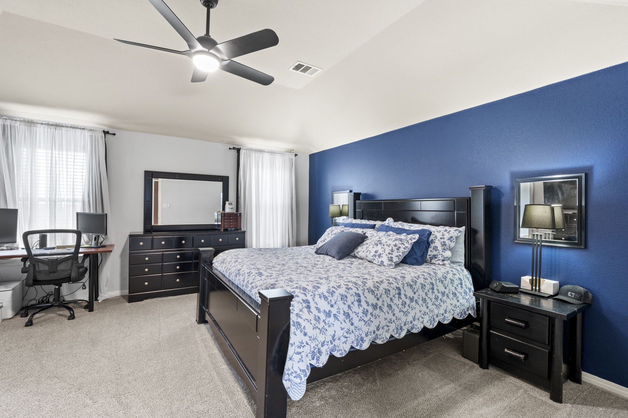 227 Sandstone Trail Buda, TX 78610 - Photo 11 of 33 Carpeted bedroom featuring a vaulted ceiling with a modern ceiling fan, a prominent accent wall, and multiple windows with blinds and sheer curtains