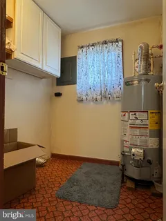 a room with water heater and wooden cabinets