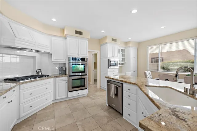 a large kitchen with stainless steel appliances granite countertop a stove sink and cabinets