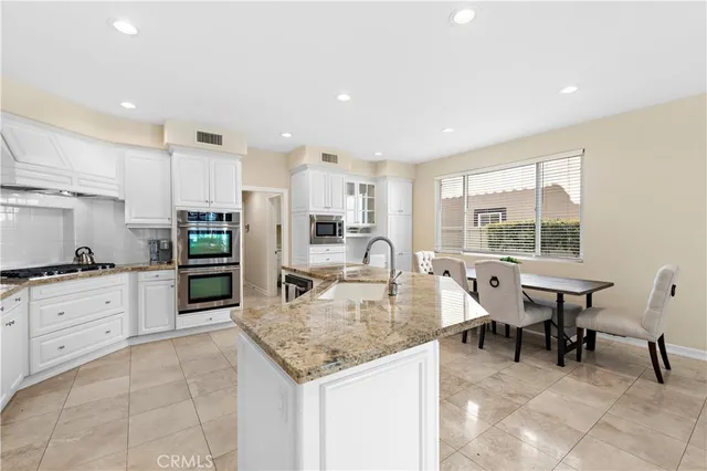 a kitchen with stainless steel appliances granite countertop a table chairs sink refrigerator and cabinets