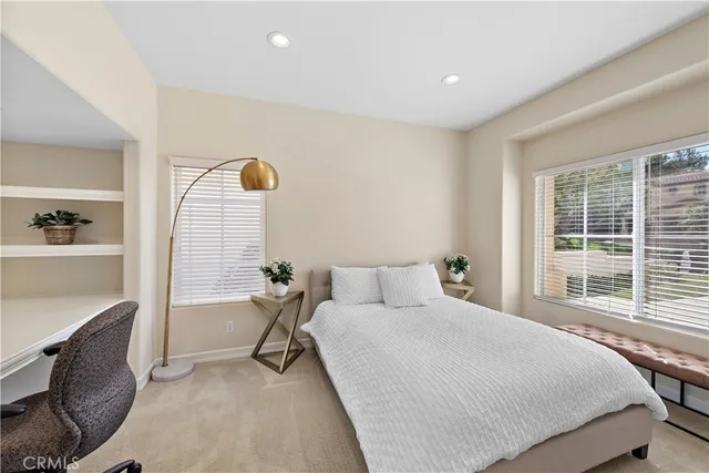 a bedroom with a bed a table and windows