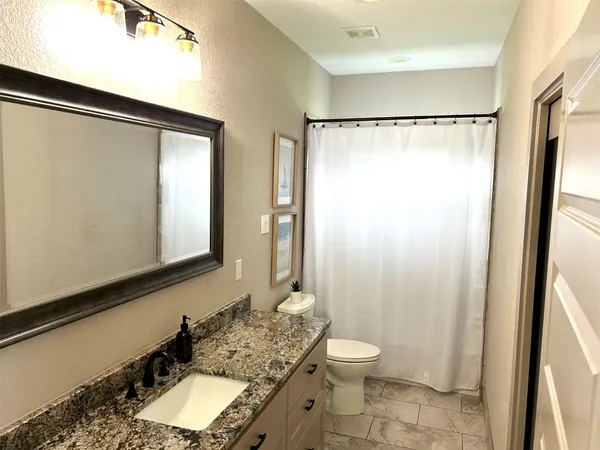 a bathroom with a granite countertop sink toilet and shower