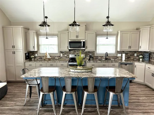 a kitchen with stainless steel appliances kitchen island granite countertop a dining table chairs and white cabinets
