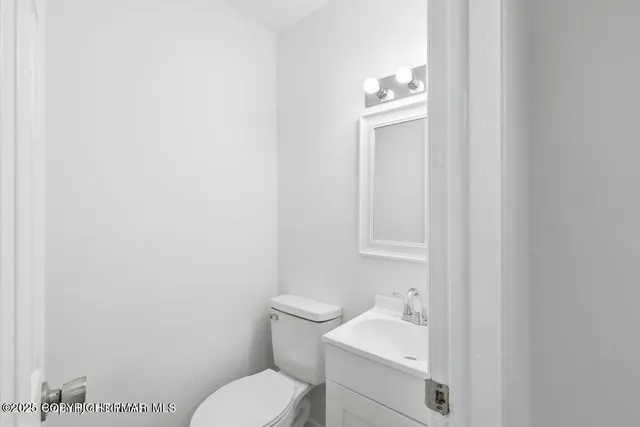 a bathroom with a toilet sink vanity and mirror
