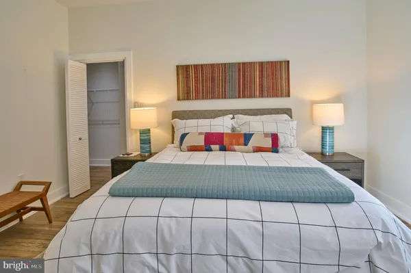 a bedroom with a bed and a lamp on dresser