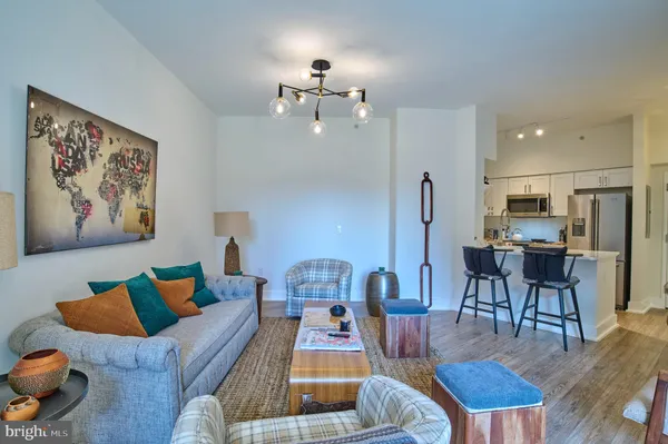 a living room with furniture kitchen view and a chandelier