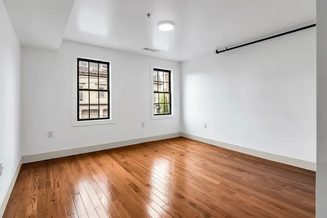 an empty room with wooden floor and windows