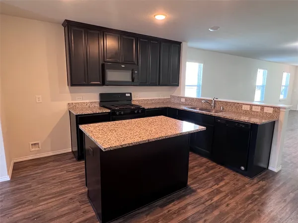 a kitchen with granite countertop kitchen island wooden floors and wooden cabinets