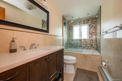 a bathroom with a sink a toilet a mirror and bathtub