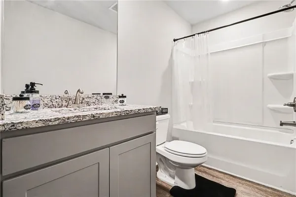 a bathroom with a granite countertop sink toilet a mirror and shower