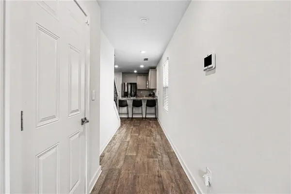 a view of a hallway with wooden floor and a bathroom