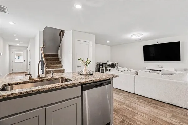 a kitchen with stainless steel appliances granite countertop a sink and a flat screen tv