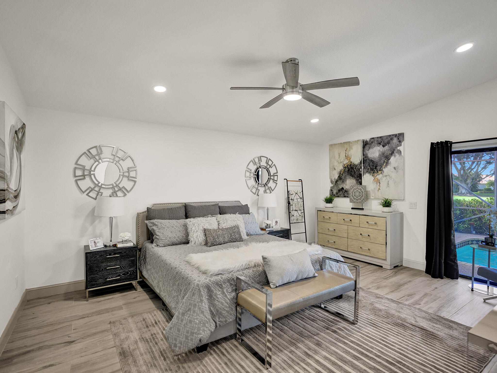 10698 Crystal Lake Drive Boca Raton, FL 33428 - Photo 16 of 48 a spacious bedroom with a bed a dresser and paintings on the wall