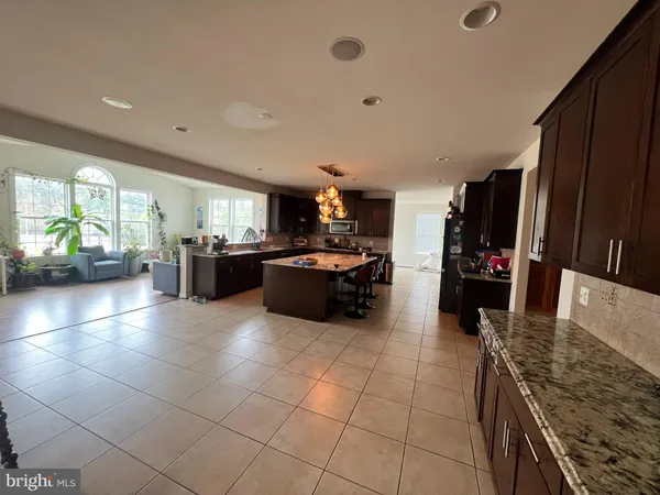 a large kitchen with granite countertop a large counter top stainless steel appliances and cabinets