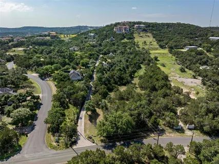 an aerial view of a residential houses with outdoor space and trees all around