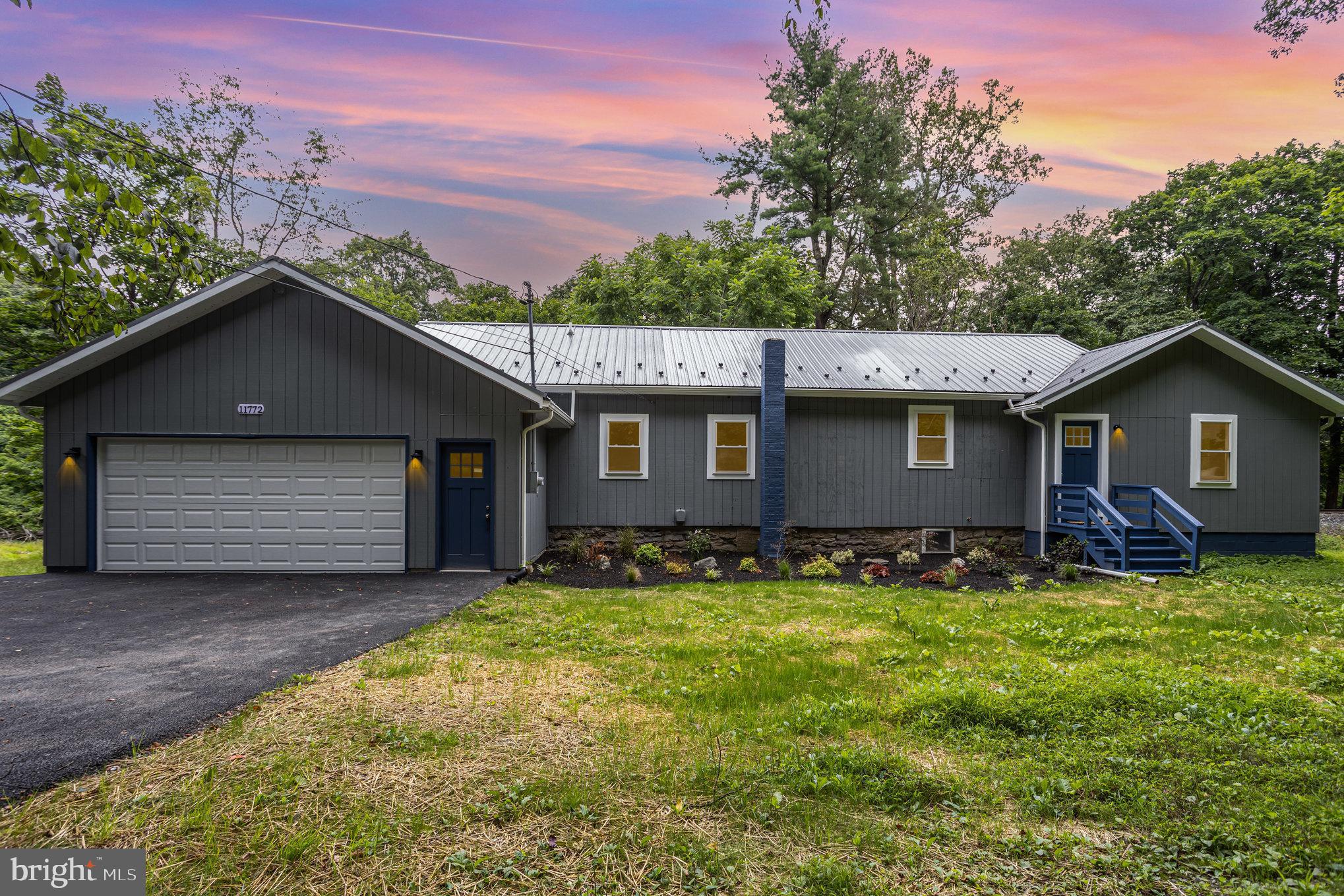 a front view of house with yard and trees in the background