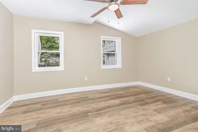 a view of an empty room with a window and wooden floor