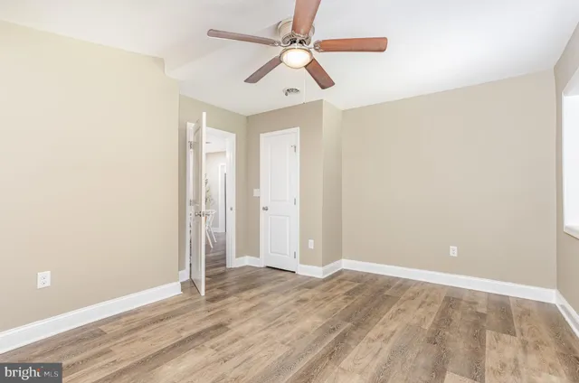 an empty room with wooden floor ceiling fan and windows