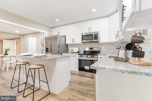 a kitchen with stainless steel appliances granite countertop a sink a stove a microwave a refrigerator and cabinets