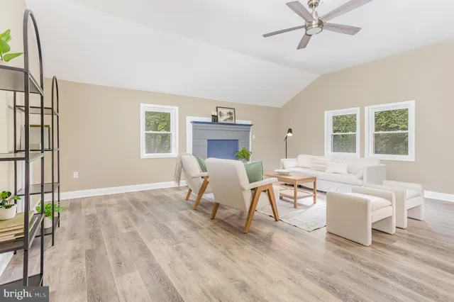 a living room with couches a fireplace and a dining table with wooden floor