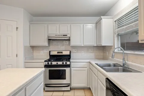 a kitchen with white cabinets and appliances