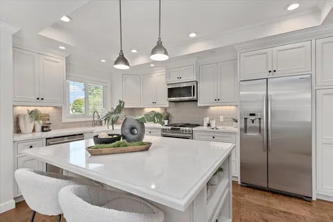 a kitchen with kitchen island a white counter top space cabinets and stainless steel appliances