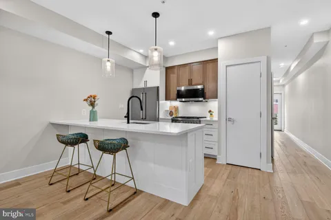 a kitchen with kitchen island granite countertop a sink cabinets and wooden floor