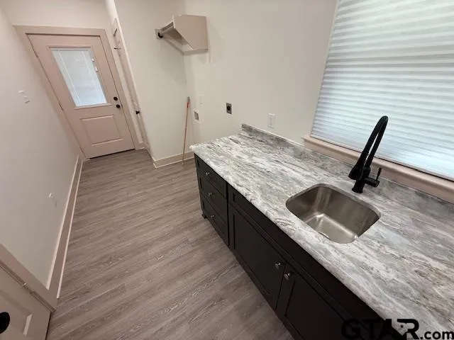 a kitchen with granite countertop white cabinets a sink and wooden floor