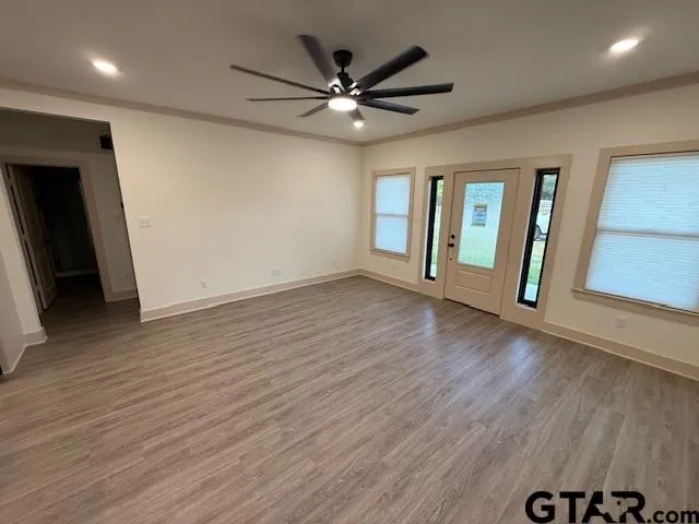 an empty room with wooden floor and windows
