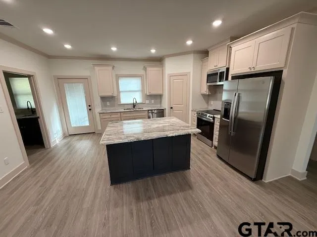 a kitchen with stainless steel appliances granite countertop a refrigerator a sink dishwasher a stove and white countertops with wooden floor