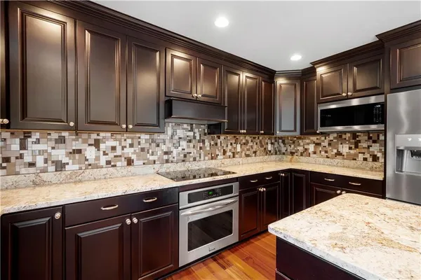 a kitchen with stainless steel appliances kitchen island granite countertop a sink stove and refrigerator