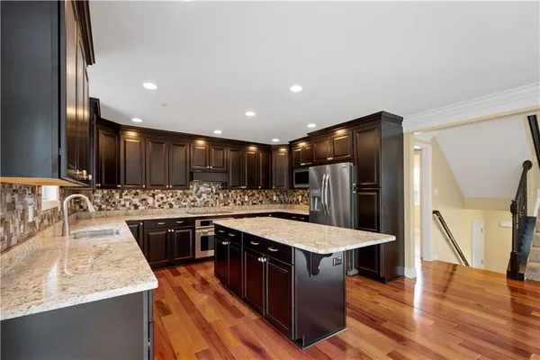 a large kitchen with stainless steel appliances granite countertop a sink and a refrigerator