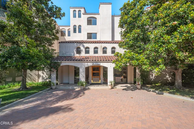 a front view of a building with yard and trees