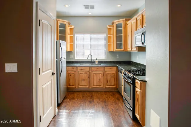 a view of a livingroom with a fireplace a ceiling fan and a kitchen view