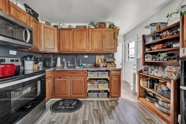 a kitchen with stainless steel appliances granite countertop a stove top oven a dining table and chairs with wooden floor
